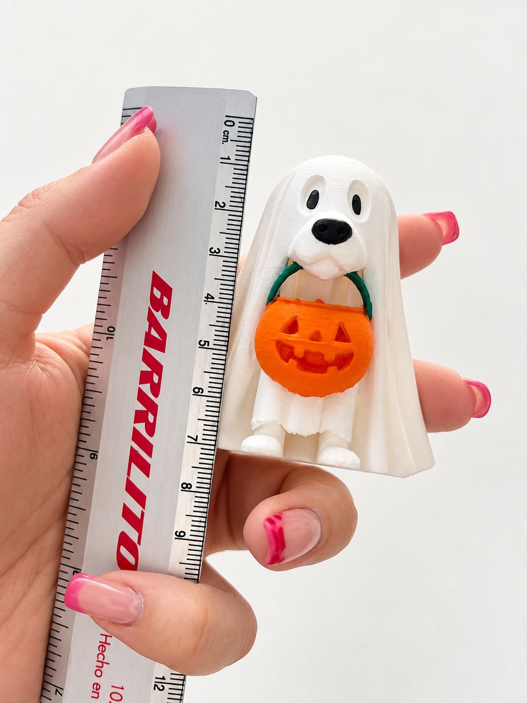Perrito fantasma junto a una regla para mostrar su tamaño